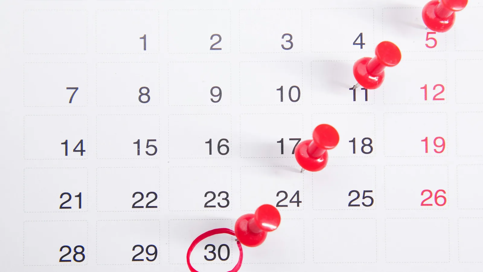 Calendario con fechas marcadas con chinchetas rojas, plazos de prescripción de una deuda mercantil