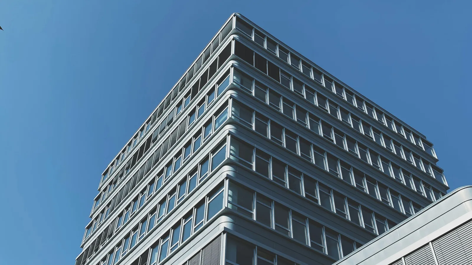 Fachada de vidrio de un edificio corporativo bajo cielo azul, despacho de abogados para empresas en Guadalajara
